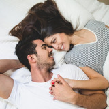 Couple-lying-bed-holding-hands-looking-into-each-other-s-eyes_23-2147596021